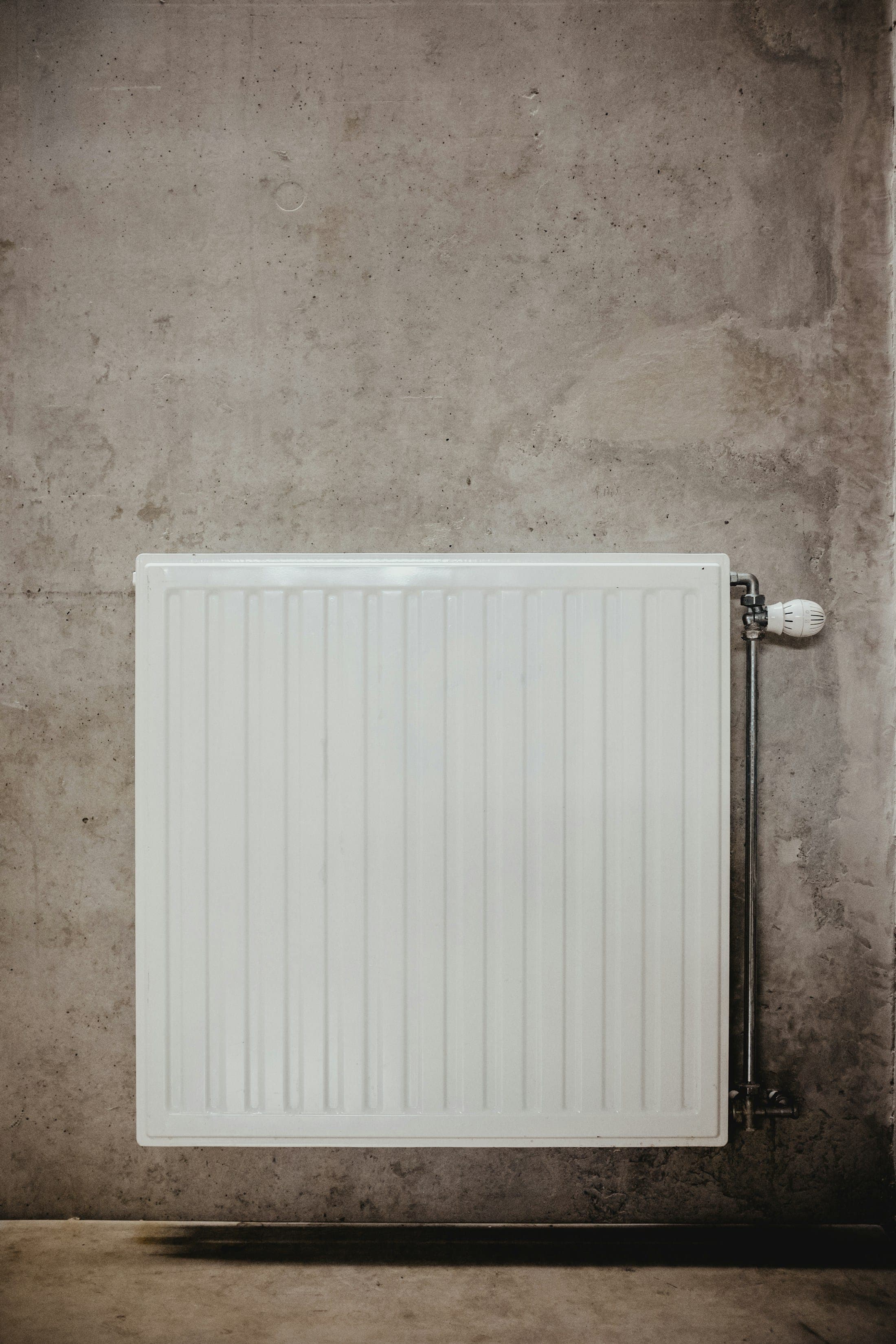 Radiateur contemporain avec robinet thermostatique sur un mur en béton